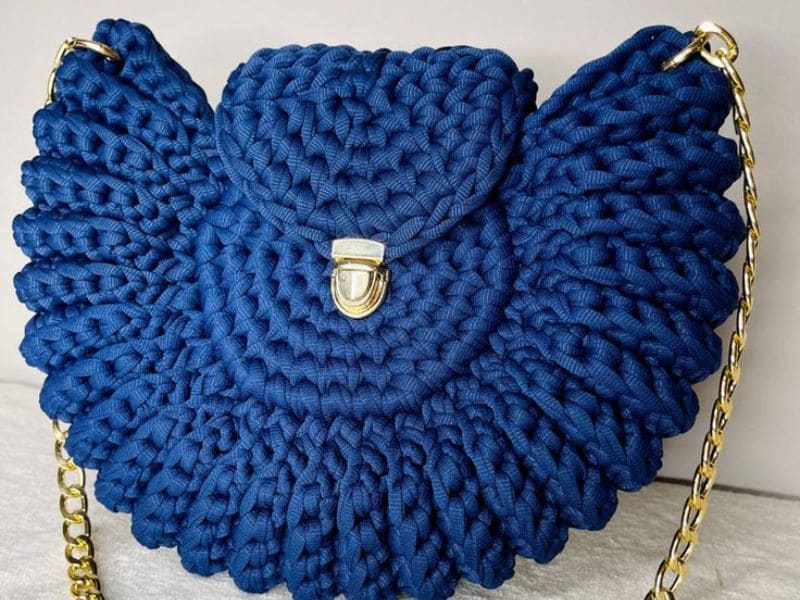 Bolsa de crochê azul de luxo com detalhes em corrente dourada e fecho metálico.