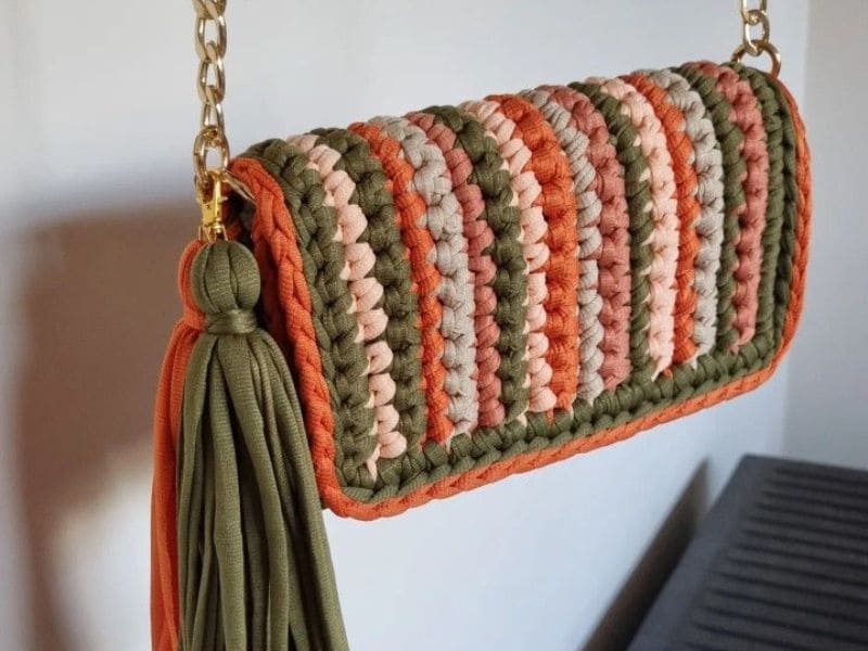 Bolsa de crochê de fio de malha moderna com alça de corrente dourada e tassel verde oliva.