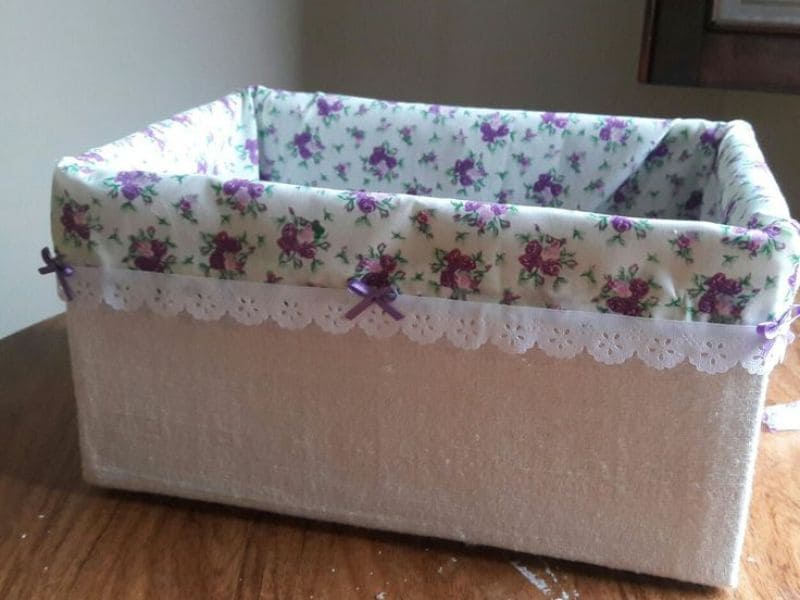 Caixa organizadora de papelão decorada com tecido floral e detalhes em renda.
