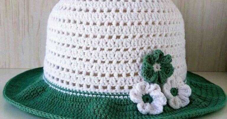 Chapéu de praia bucket em crochê branco com detalhes e aba verde, decorado com flores de crochê brancas e verdes.
