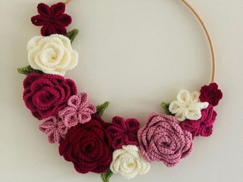 Guirlanda decorativa com flores de crochê em tons de rosa, branco e vermelho, ideal para quarto.
