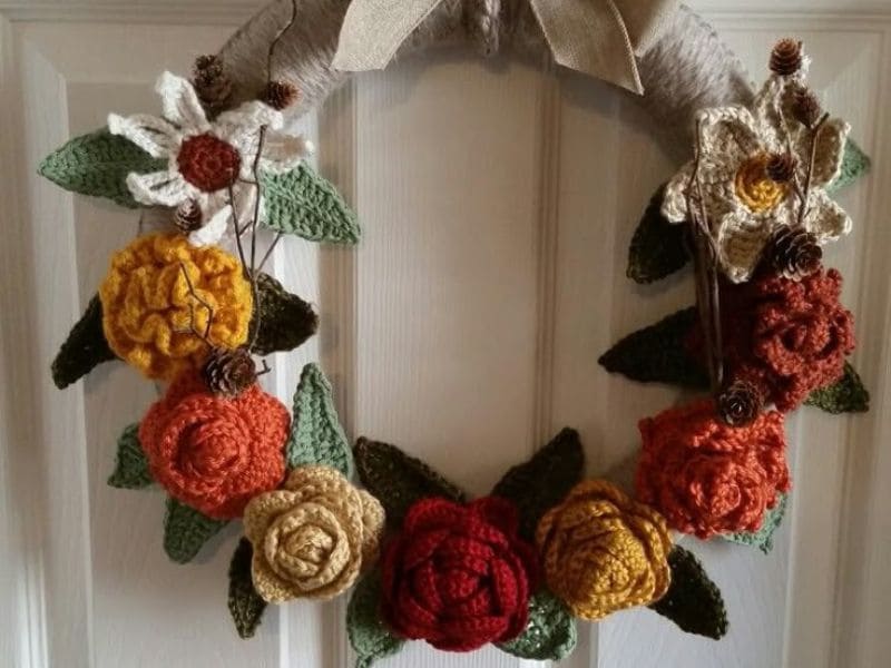 Guirlanda de crochê com flores em tons terrosos pendurada em uma porta branca, ideal para decoração de quarto.