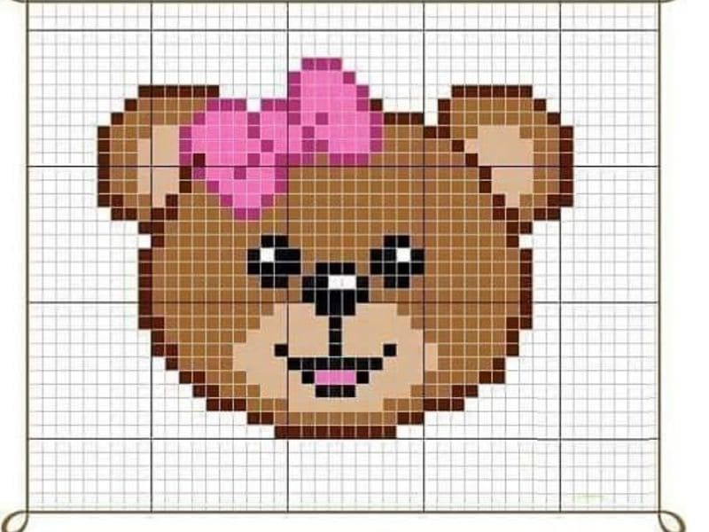 Gráfico de ponto cruz mostrando o rosto de uma ursinha marrom com um laço rosa na cabeça.